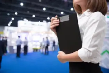 Messehalle, junge Frau hält Clipboard