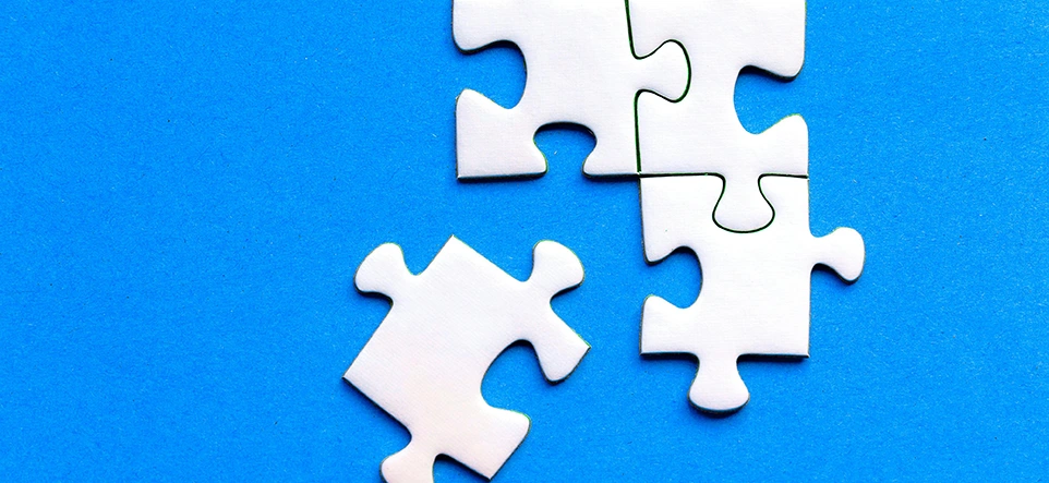 Vier weiße Puzzleteile vor blauem Hintergrund